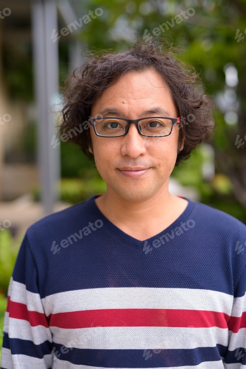 Preview: Face of Japanese man with curly hair wearing eyeglasses in the rooftop garden