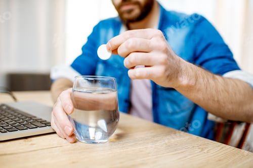 Preview: Man taking pills during the work at home