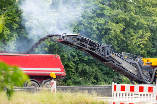 Preview: Asphalt milling and grinding machine at road repair and construction site throwing shredded old