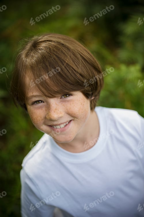 Preview: A boy in a white tee-shirt looking up at the camera.