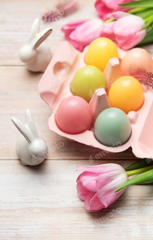 Preview: Easter eggs with ceramic bunnies and pink tulips decorating wooden table