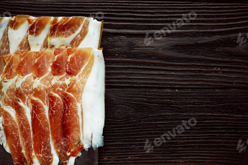 Preview: Parma ham slices on dark wooden background, top view, flat lay