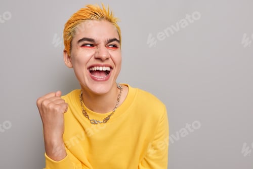 Preview: Pretty optimistic punk girl feels like winner celebrates success clenches fist looks happily away we