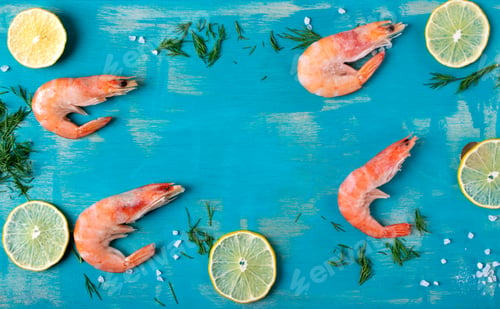 Preview: Shrimps on turquoise colored wooden board with lime slices. Frozen boiled seafood product.