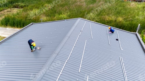 Preview: Men technicians mounting photovoltaic solar moduls on rooftop of warehouse.