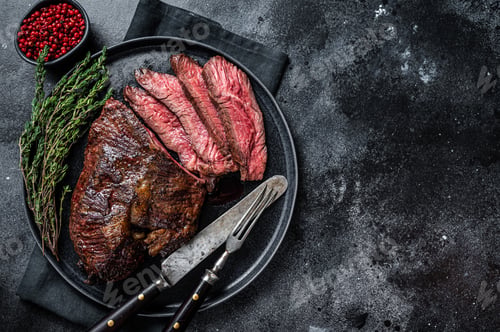 Preview: Grilled hanger or Onglet beef meat steak on a plate with thyme. Black background.