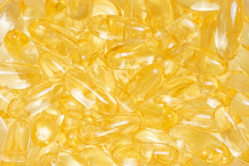 Preview: Pile of golden color fish oil capsules close-up top view.