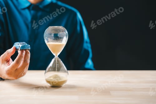 Preview: Hand holding car toy, hourglass running, symbolizing time passing for car loan payment, finance