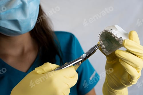 Preview: Dentist practicing on a model of prosthetic teeth with a dental mirror