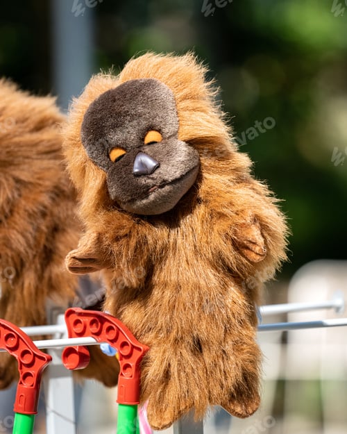 Preview: Plush animal toys hang side-by-side from a white picket fence in the warm sun