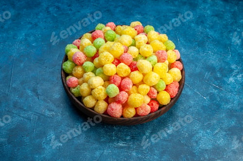 Preview: Front close view of delicious coloured sweets in a small brown pot on the right side on blue