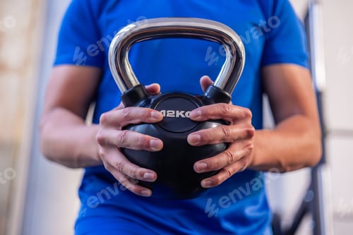 Preview: close-up of young athlete's hands holding 12 kg kettlebell during gym workout