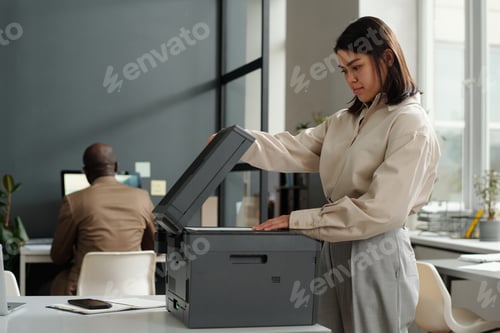 Preview: Young secretary or female office worker putting paper on scanning glass