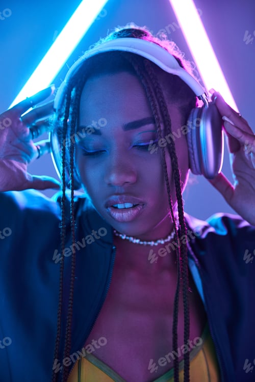 Visualização: jovem afro-americana em dreadlocks e fones de ouvido em estúdio com luz fluorescente azul