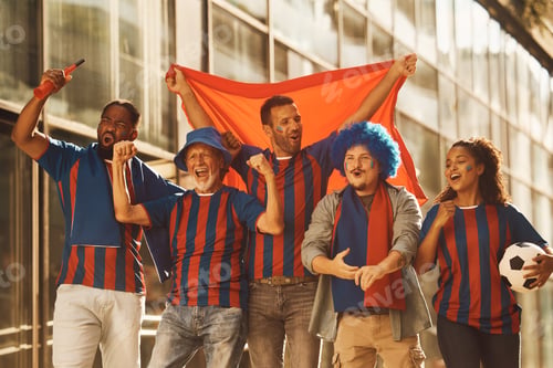 Preview: Multiracial group of cheerful soccer fans celebrating on the street.