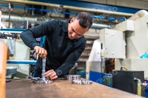 Preview: Man measuring metal pieces using micrometer at factory