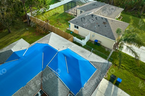 Preview: Top view of leaking house roof covered with protective tarp sheets against rain water