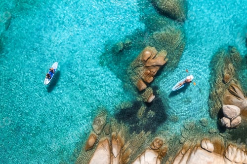 Preview: Aerial view of two stand up paddle boards with tourists paddling in the clear turquoise water