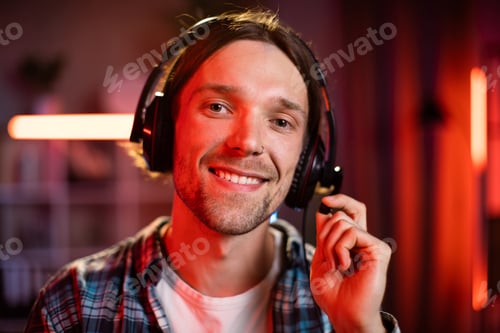 Preview: Handsome young man wearing headset while working at home during evening time.