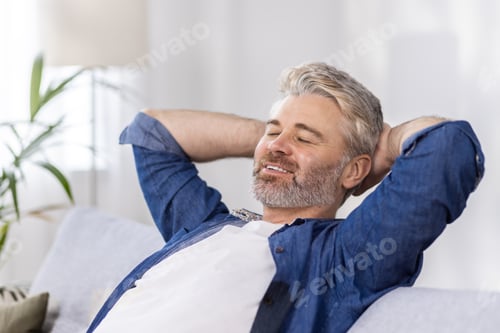 Preview: Close-up photo. Senior gray-haired man sitting relaxed on sofa at home and resting, napping