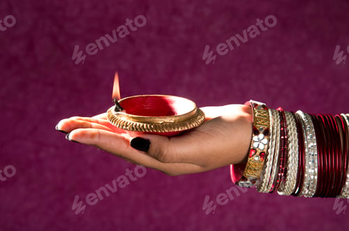 Preview: Female hand holding lit earthen lamp at Diwali festival in India
