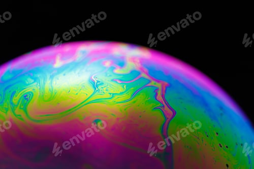 Preview: Rainbow soap bubble on a black background. Close-up of a colorful surface.