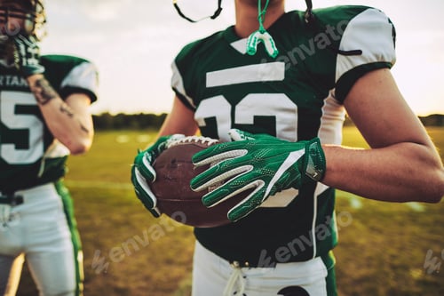 Preview: American football quarterback standing with a teammate during practice