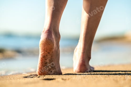 Preview: Close up of woman feet walking barefoot on sand leaving footprints on golden beach. Vacation, travel