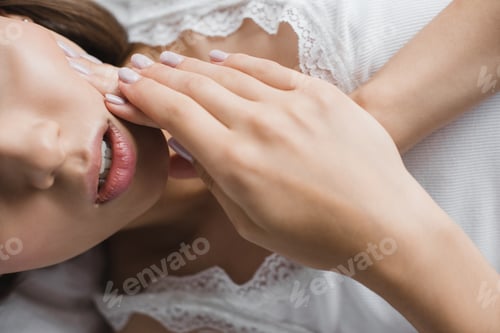 Preview: cropped shot of young woman suffering from toothache while lying in bed