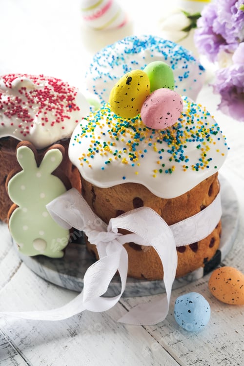 Preview: Traditional Easter sweet bread or cakes with white icing and sugar decor and quail eggs over white w
