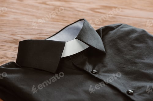 Preview: close-up shot of clerical shirt with white collar on wooden surface