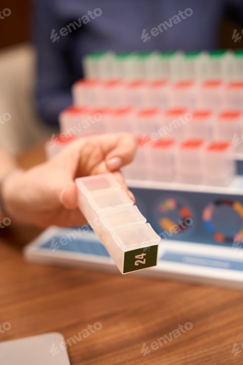 Preview: Practitioner holding multi-colored case for pills with compartments