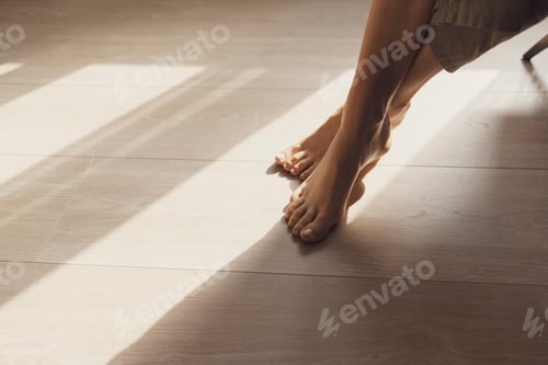 Preview: Female feet on hardwoord floor and sunlight
