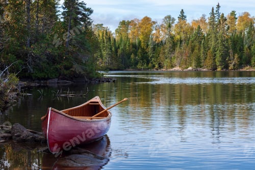 Preview: Red wooden canoe on the shore of a Boundary Waters lake in morning light during autumn
