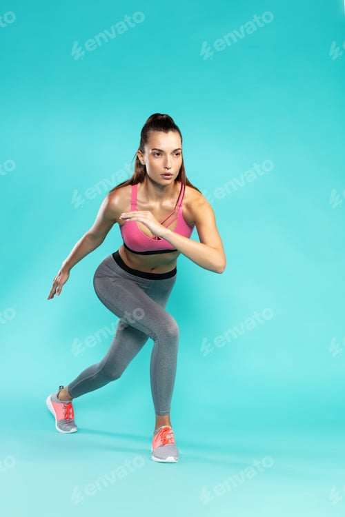 Preview: Workout. Full length of young attractive woman in sportswear exercising while standing against blue