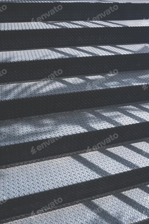 Preview: Sunlight and shadow on surface of black metal staircase of nature skywalk way at public park