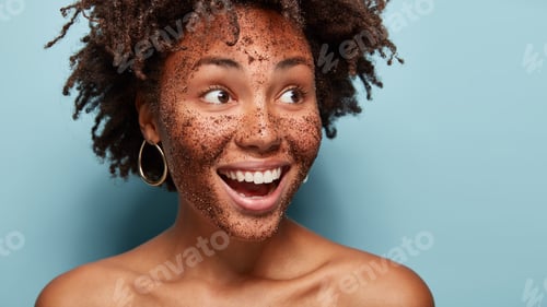Preview: Topless happy woman applies natural coffee mask, looks aside with cheerful expression, shows white t