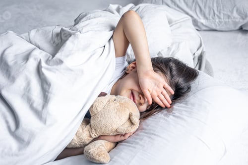 Preview: A cute little girl lies in bed and doesn't want to get up.