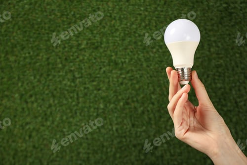 Preview: A light bulb in a hand on a background of grass