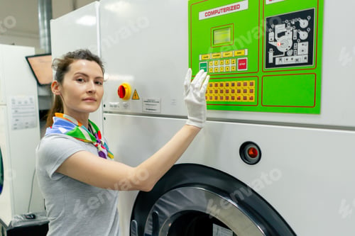 Preview: professional dry cleaner young girl looking at the camera and posing near professional washing