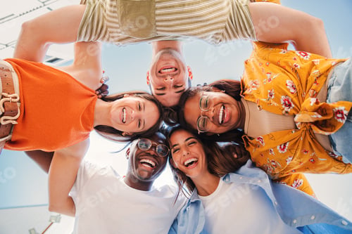 Preview: low view angle of a group of multiracial teenagers smiling and looking at camera together. Portrait