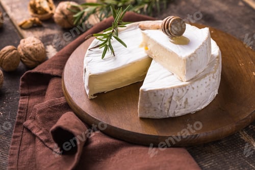 Preview: Organic farm camembert or brie cheese on a wooden board with rosemary and nuts, honey.