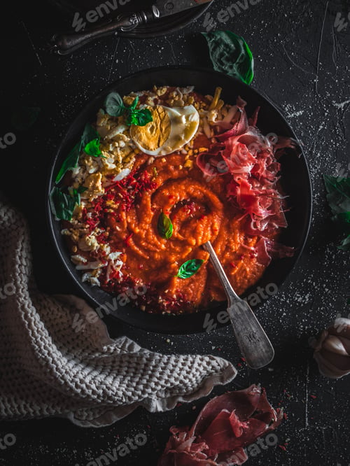 Preview: Spanish salmorejo soup with mountain bacon, basil, garlic and egg on a dark background