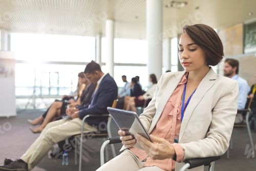 Preview: Happy young businesswoman using digital tablet during seminar in office building