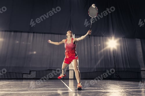 Preview: Young woman playing badminton at gym