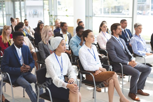 Preview: Side view of group of diverse business people attending a business seminar in office building