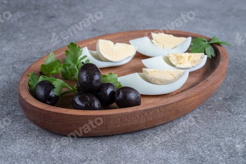 Preview: A wooden board with olives and boiled eggs