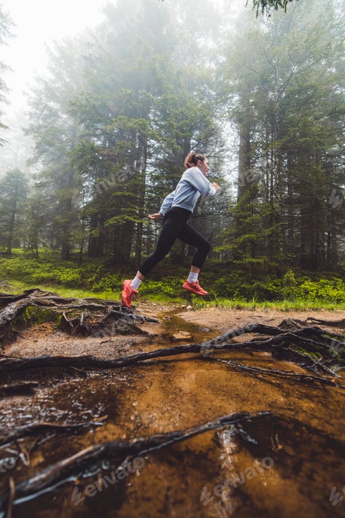 Preview: A person running through a misty forest, navigating over tree roots and muddy ground. The scene capt