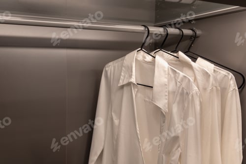 Preview: White shirts hanging in a minimalist wardrobe. Capsule closet.