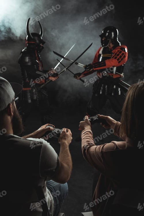 Preview: back view of man and woman playing samurai fighting in real life with gamepads on black